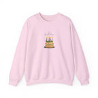 Pink crewneck sweatshirt with front birthday cake graphic and lit candles.