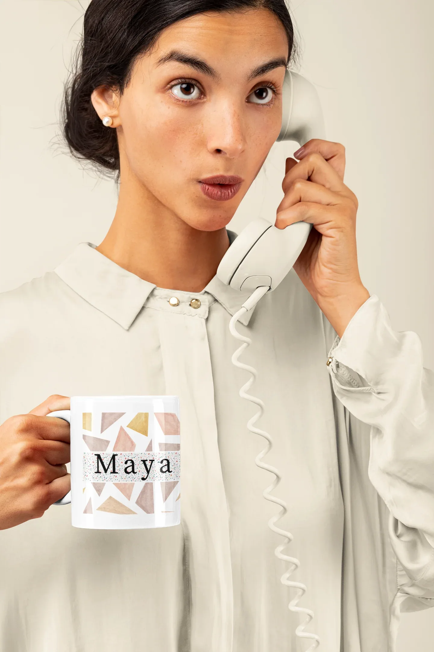 White mug held near the chest, with geometric triangles and name Maya on front