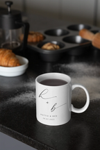 White ceramic mug with monogram h + b and date 28.07.2023, filled with tea.