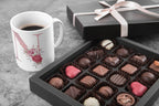 White mug with floral letter I design beside assorted chocolates in a gift box.