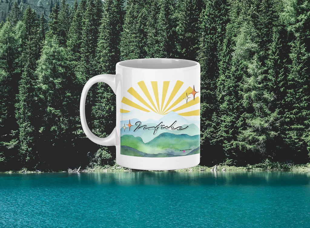 White coffee mug with sunrise rays and mountain landscape graphic, side view