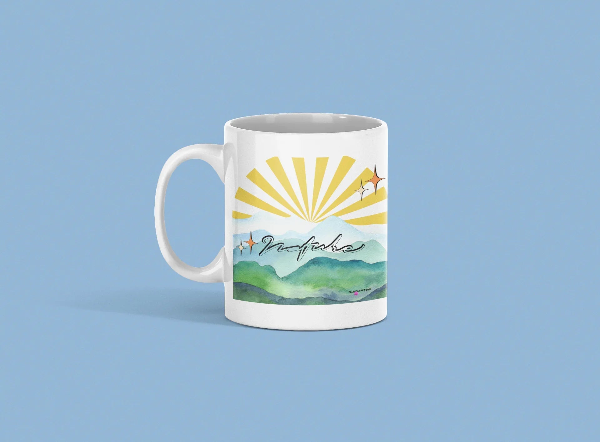 White coffee mug with sunrise rays and mountain landscape graphic, front view