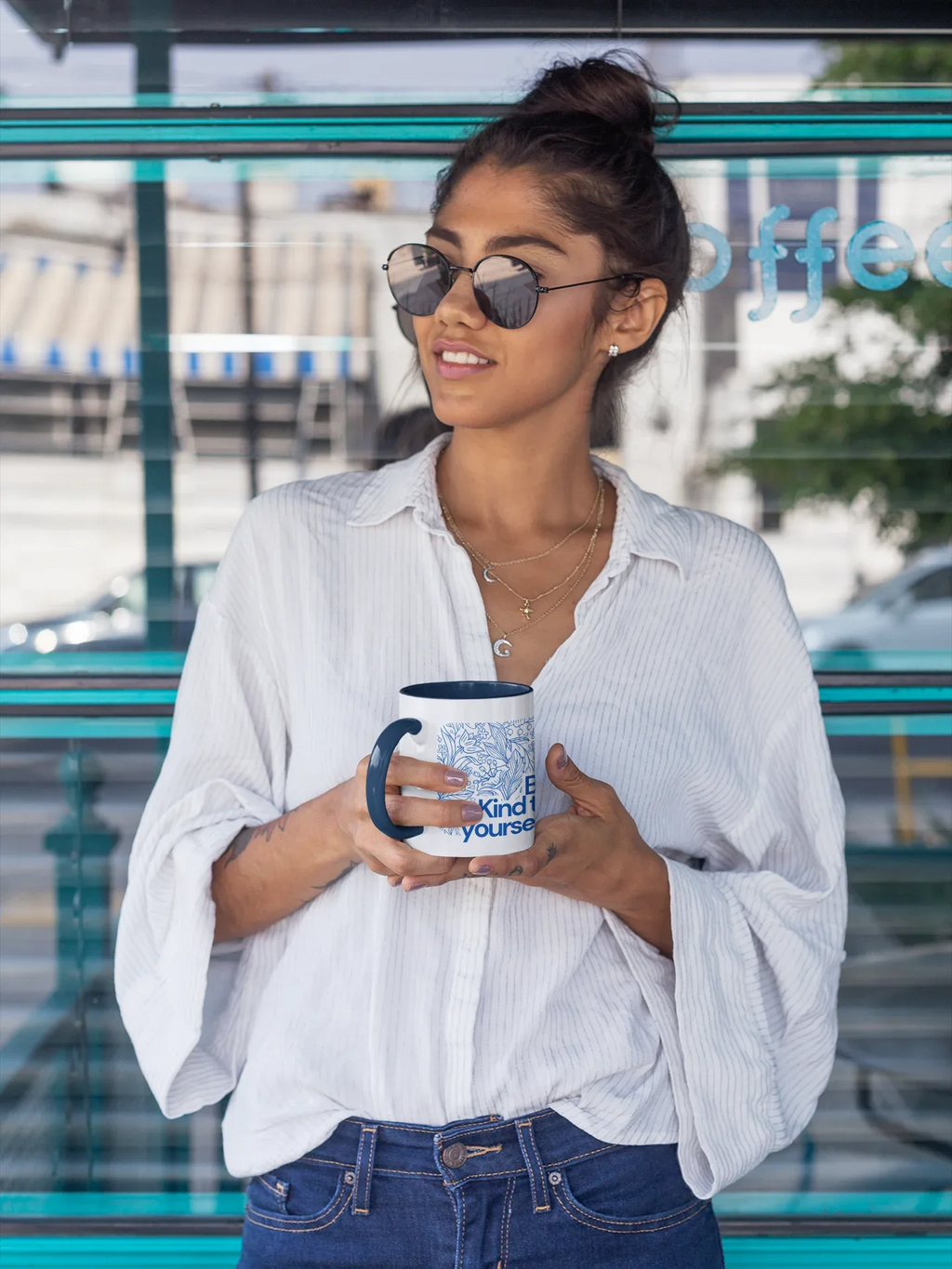 Coffee mug with dark blue finish and Be Kind to yourself text, held while smiling