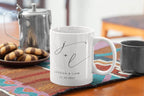 White ceramic mug with monogram j + l and date 23.06.2024, on tabletop.