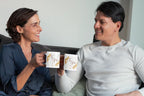 Two white wedding mugs with gold filigree and dark red 'T & M' printed