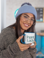 White coffee mug with “Plant Lady” graphic, held by a woman in a blue hat