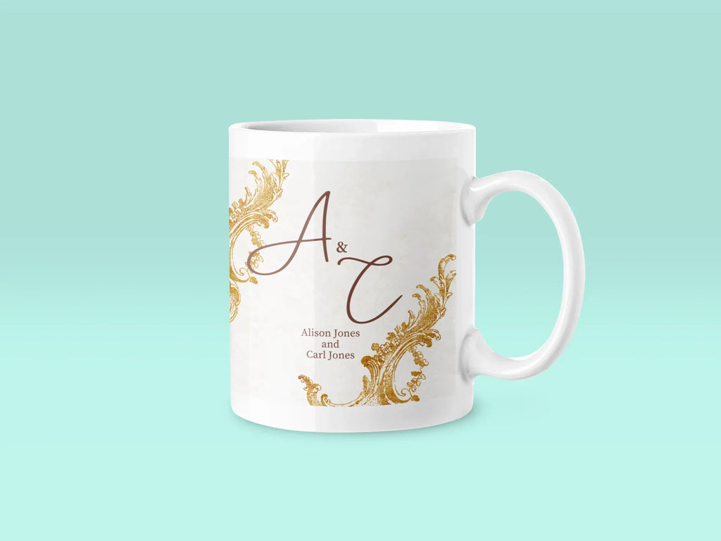 White ceramic mug with gold filigree and dark red 'A & T' monogram