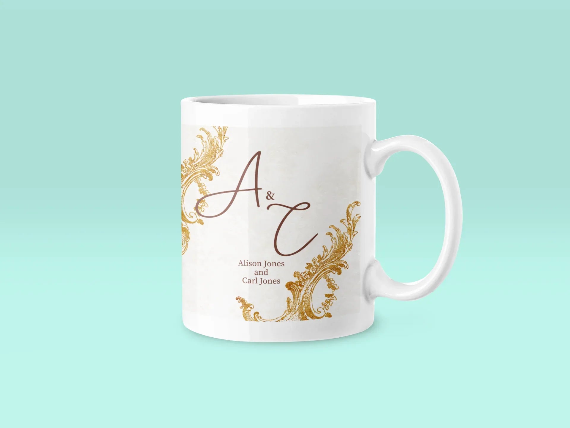 White ceramic mug with gold filigree and dark red 'A & T' monogram