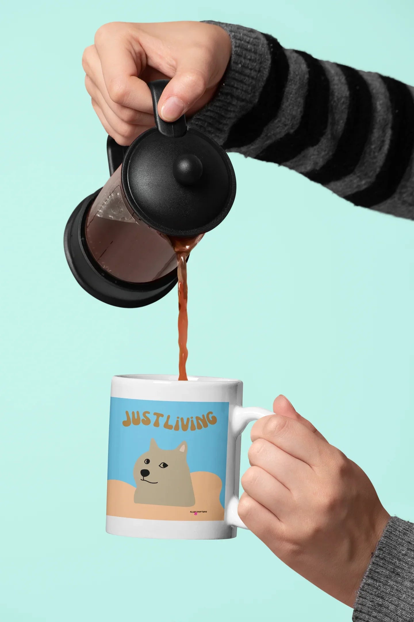 Ceramic mug with blue “JUST LIVING” dog design being filled from a kettle