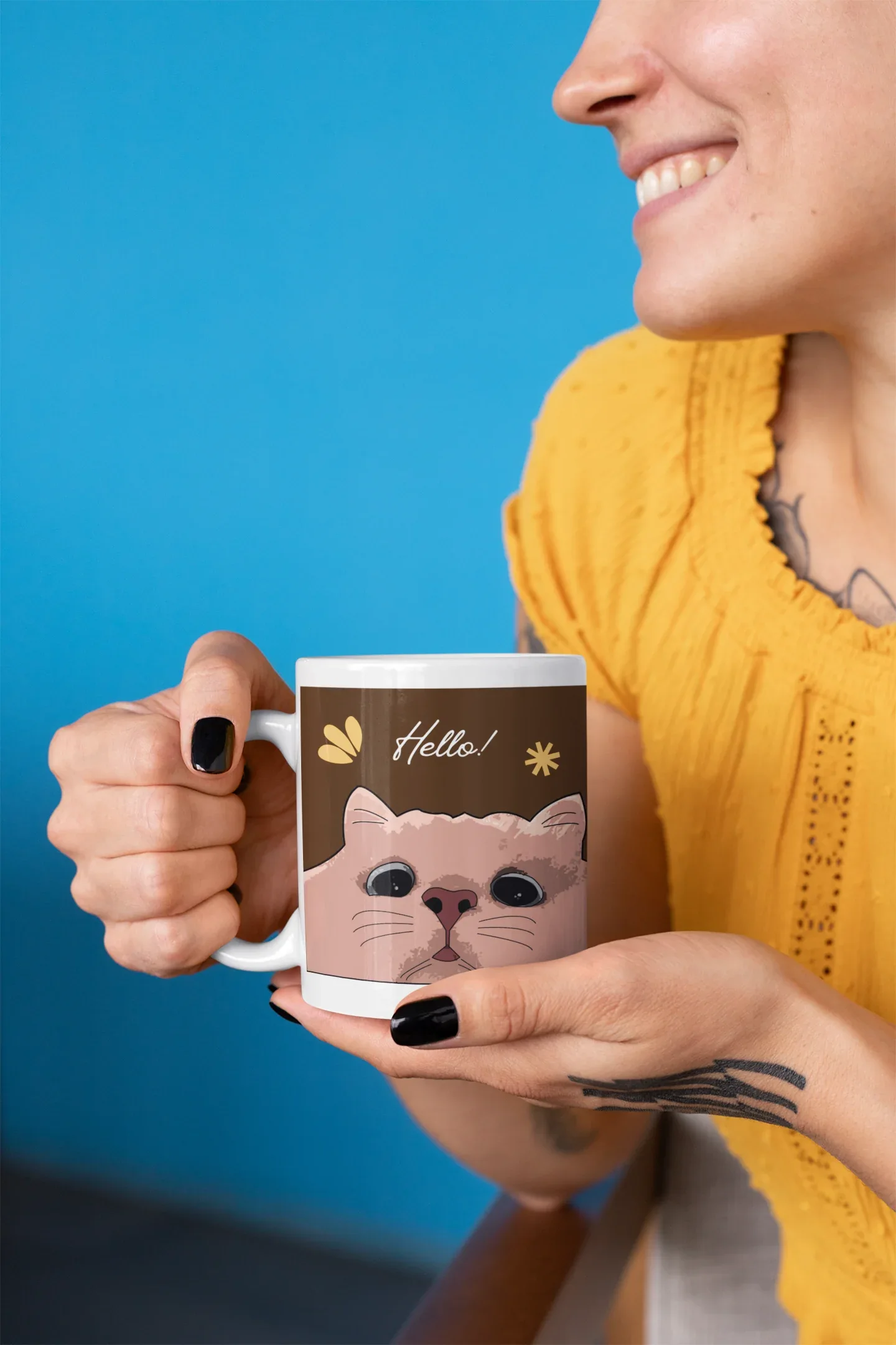 White mug with cat face and 'Hello!' graphic held in a hand