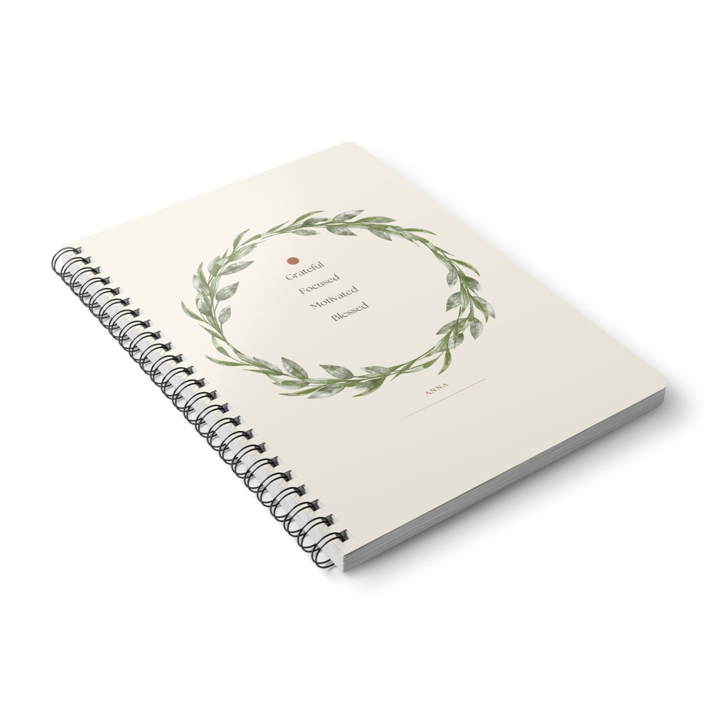 A5 spiral notebook with floral wreath cover and lined pages, angled view