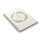 A5 spiral notebook with floral wreath cover and lined pages, angled view