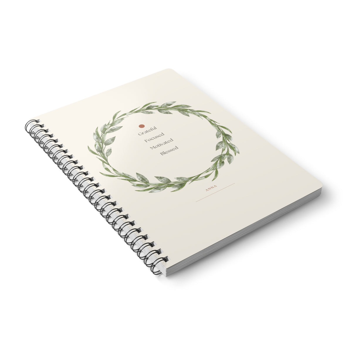 A5 spiral notebook with floral wreath cover and lined pages, angled view