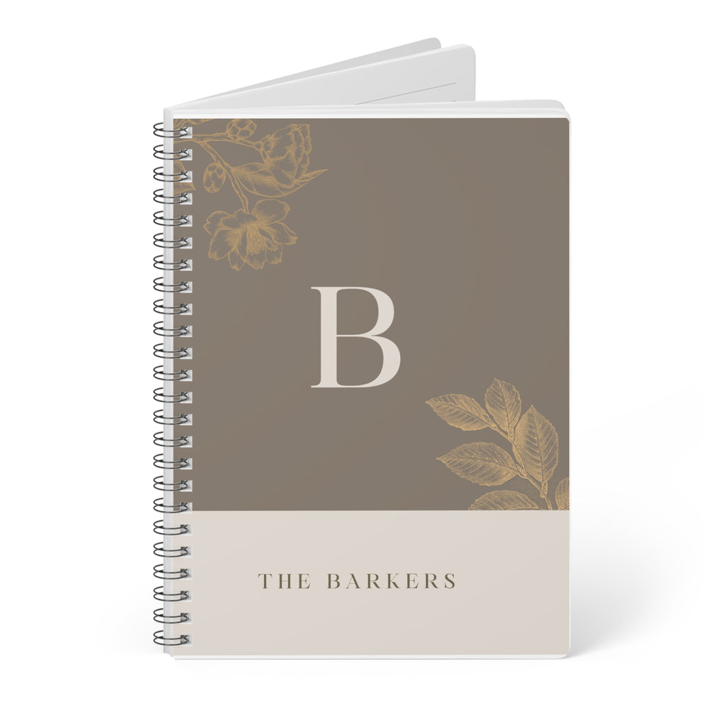 A5 notebook with taupe cover, gold monogram B, floral motifs, and stacked spiral binding.