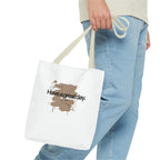 White canvas tote bag with light tan handles and brown splash “Haveagreatday.”