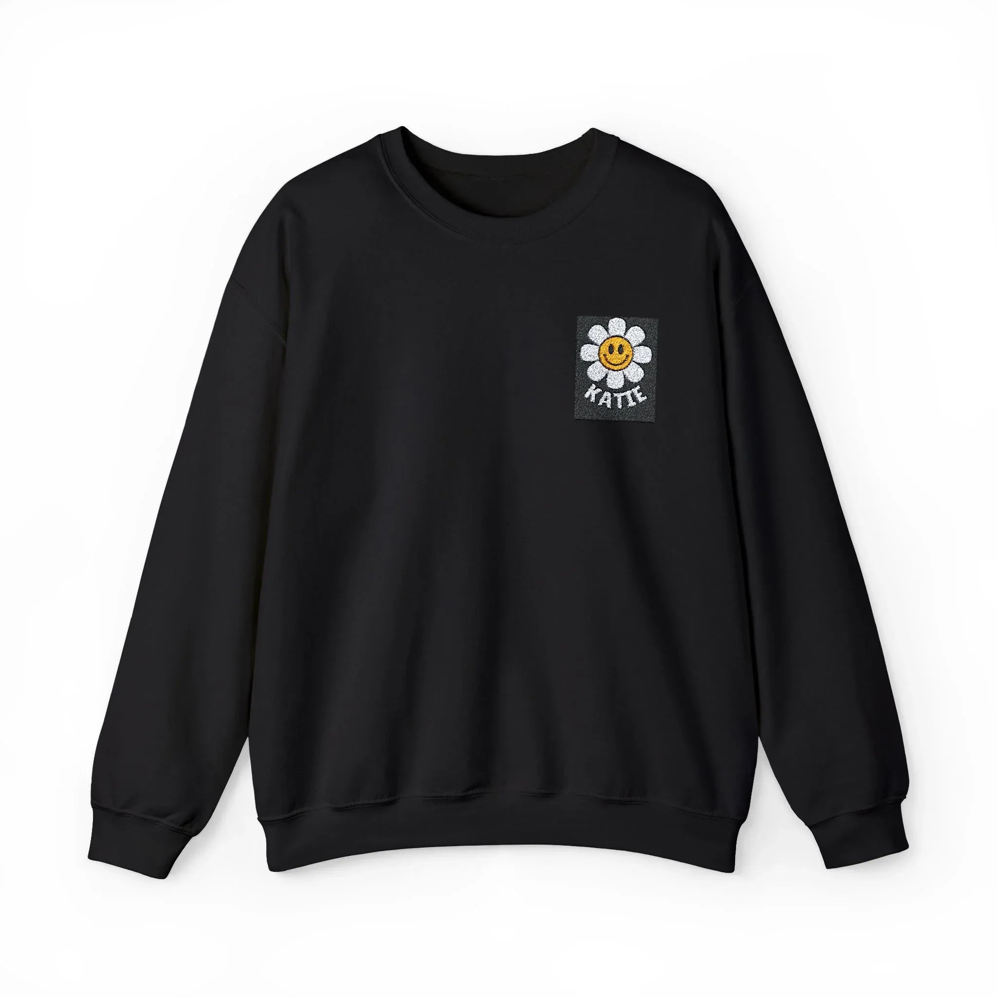 Black crewneck sweatshirt with small square flower smiley patch on chest.
