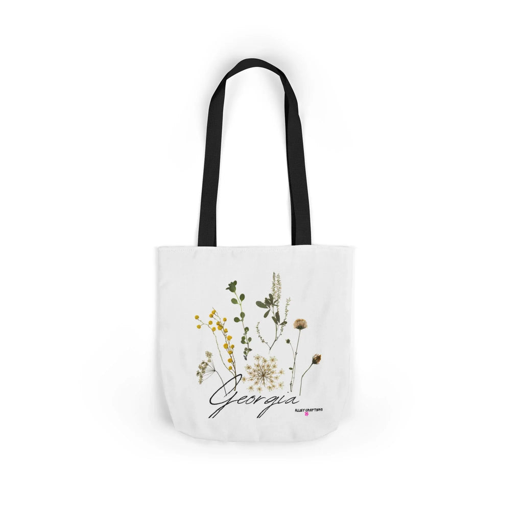 White canvas tote bag with black handle straps and botanical print centered