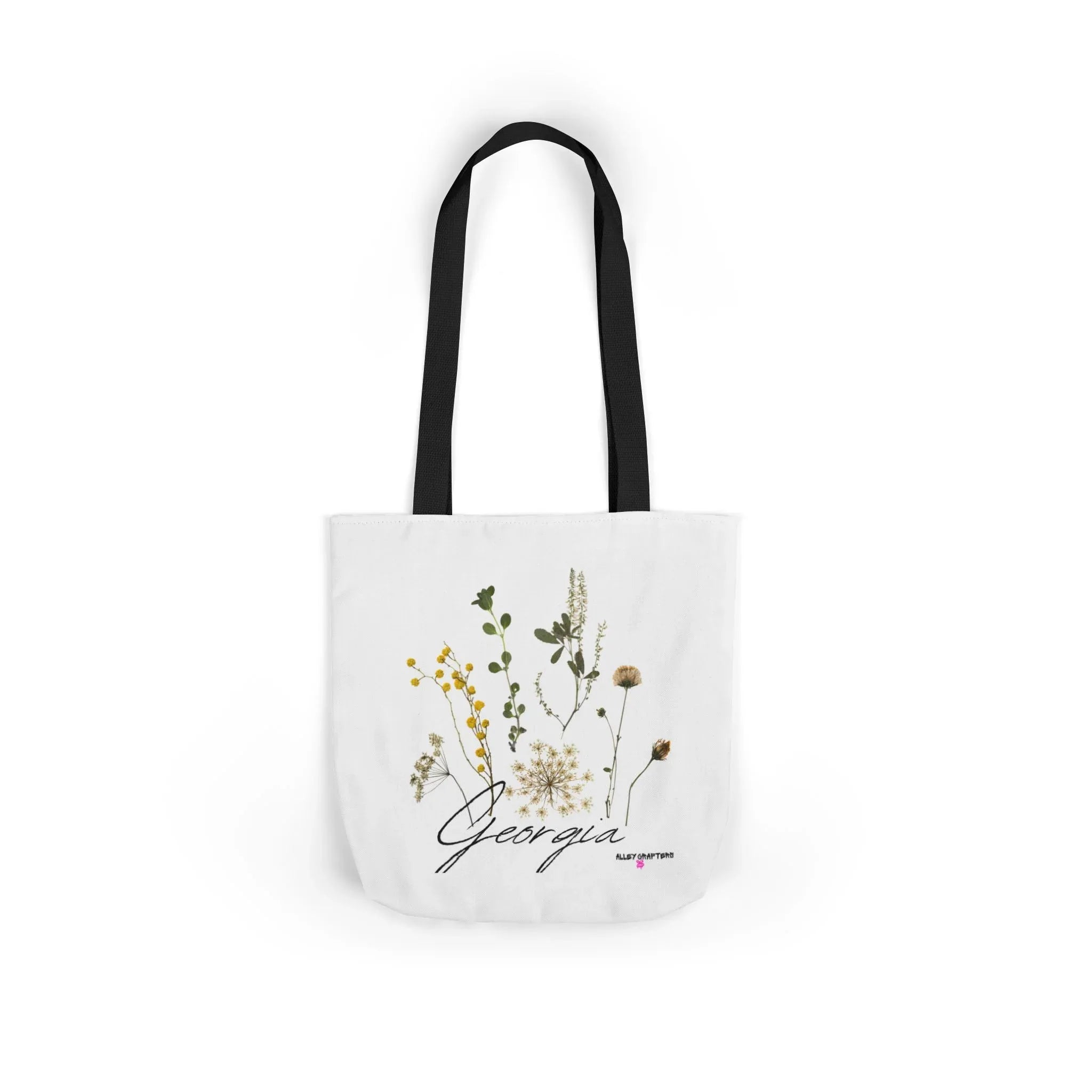 White canvas tote bag with black handle straps and botanical print centered