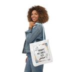 White tote bag with printed quote and colorful confetti-style accents, held at side.