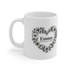 White ceramic mug with floral heart wreath and “Emma” on front
