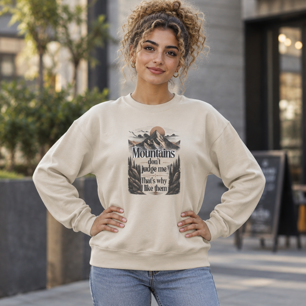 Sand sweatshirt with centered front mountain quote graphic, worn with jeans