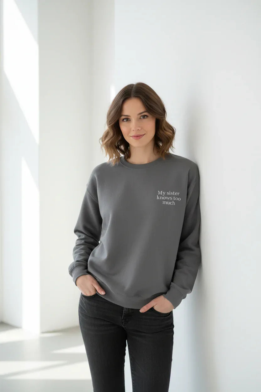Dark gray crewneck sweatshirt with small chest text, worn by a model