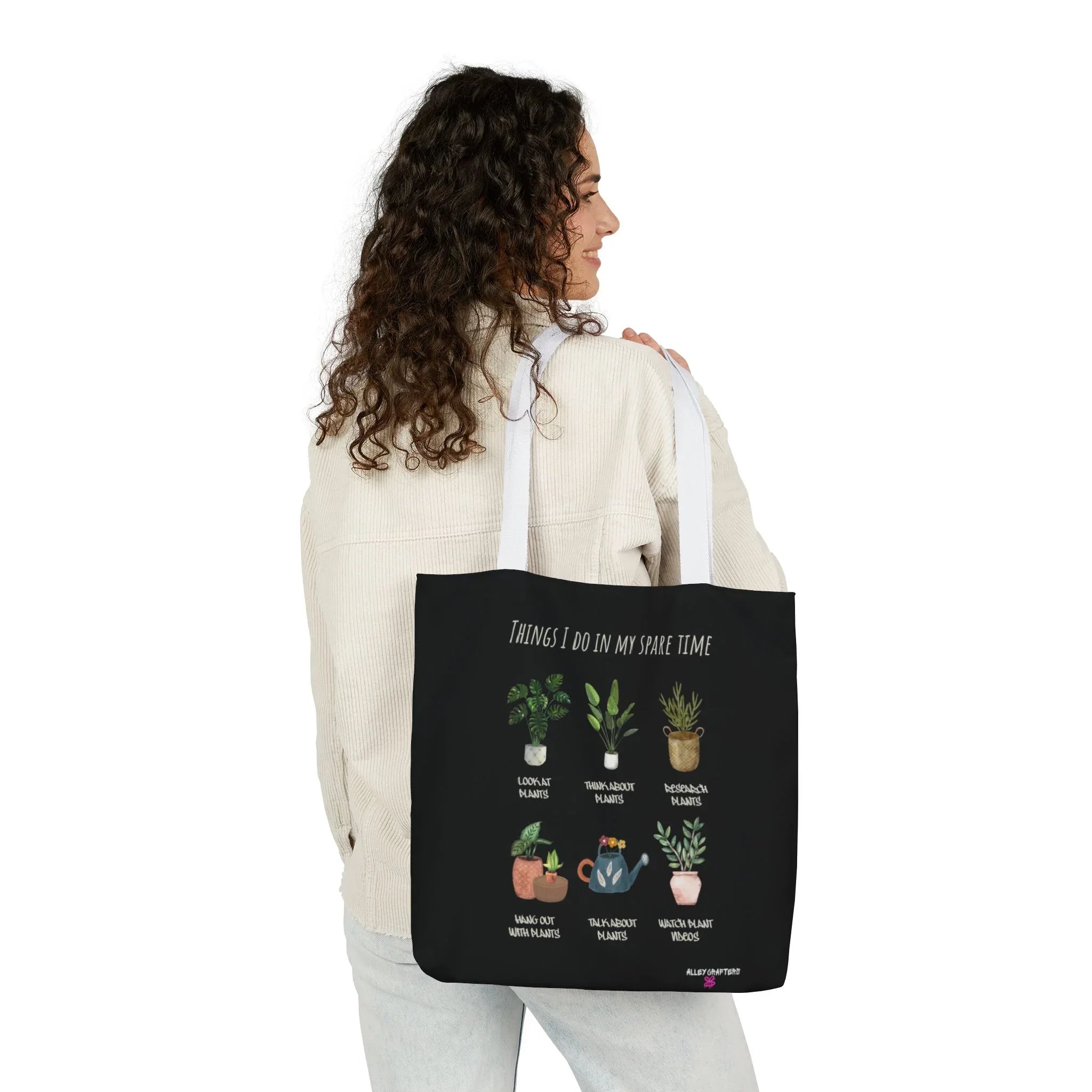 Black tote bag with white handles and plant collage print, carried at the side.