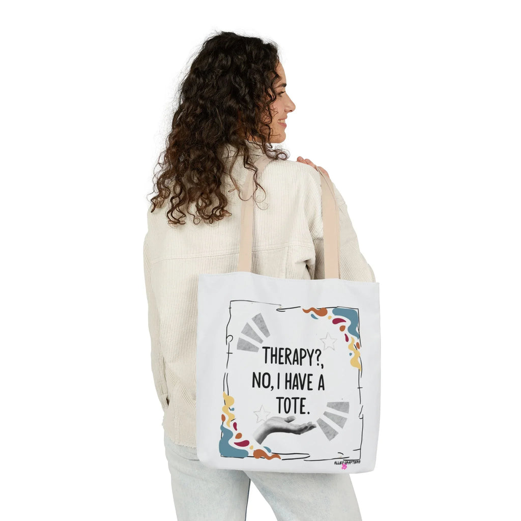 White tote bag with “Therapy?, No, I have a Tote” print and colorful border, held at side