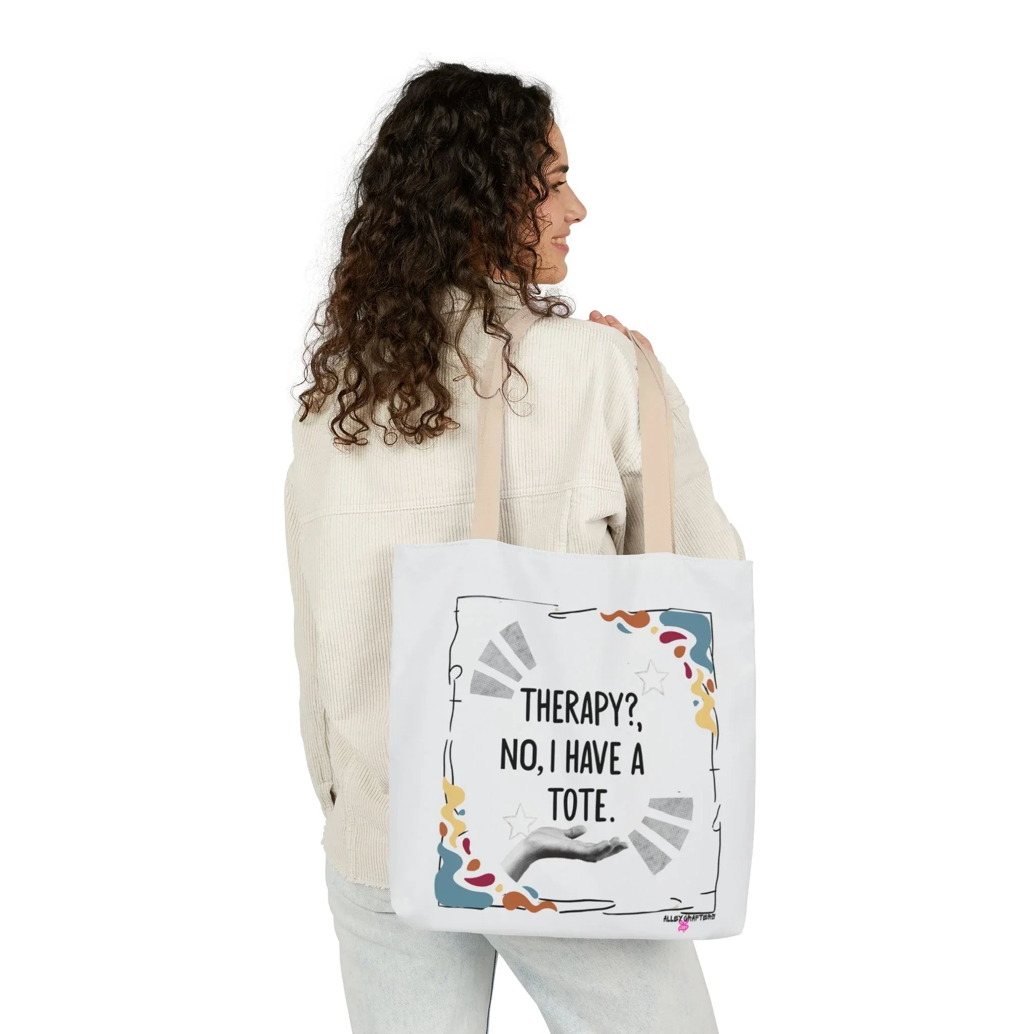 White tote bag with “Therapy?, No, I have a Tote” print and colorful border, held at side
