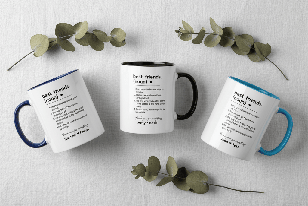 White ceramic mugs with blue and black handles, each with printed friendship quote.
