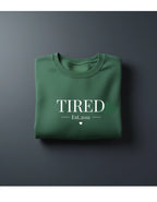 Green crewneck sweatshirt with 'TIRED' and 'Est.2011' text print