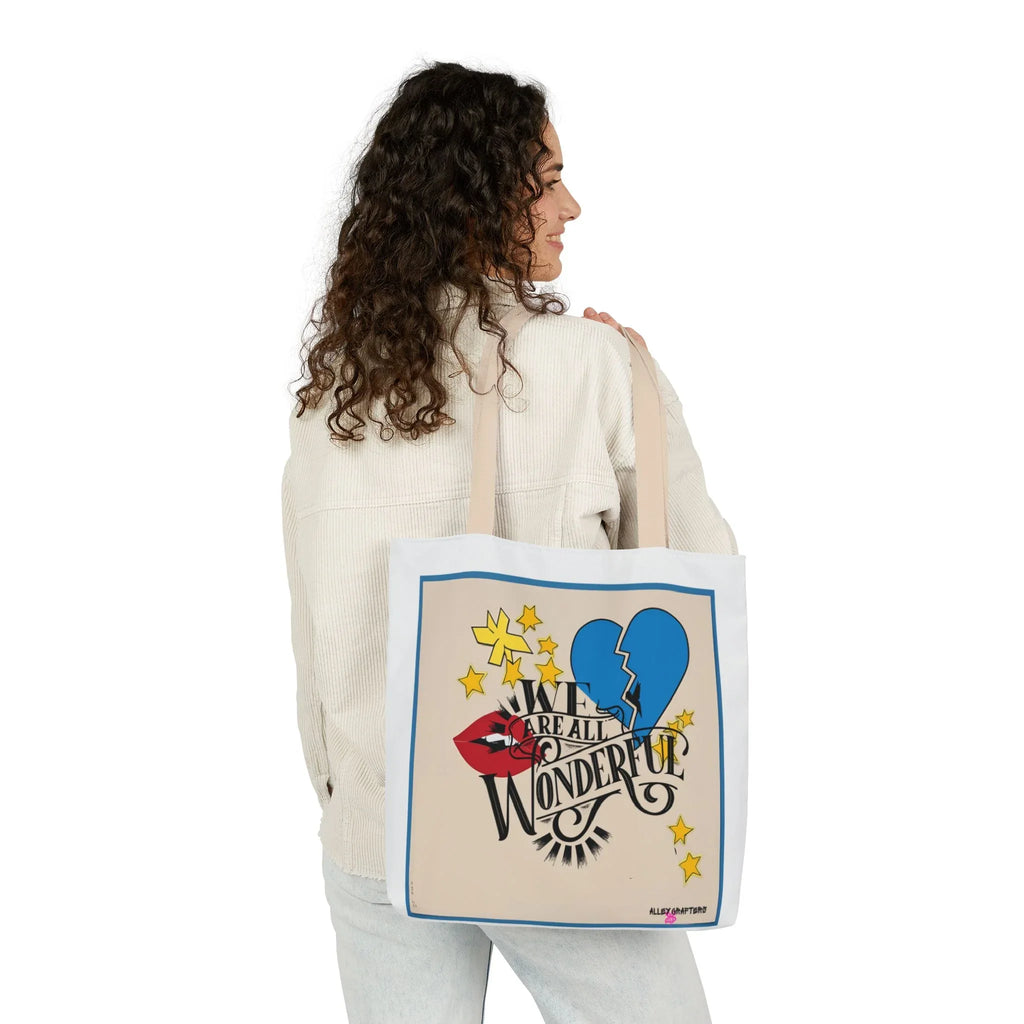 Light canvas tote bag held from the side, showing blue trim and front print
