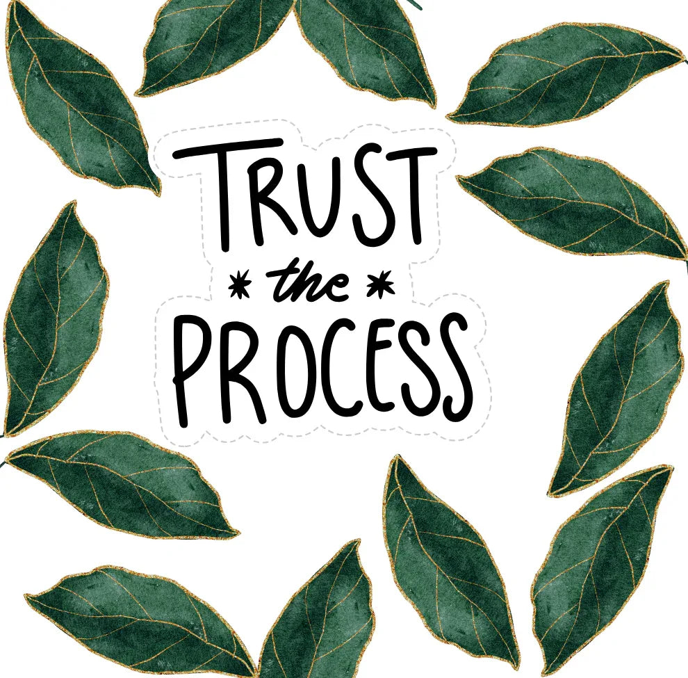 White mug close-up with green leaf border and “TRUST the PROCESS” lettering