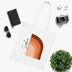 White cotton tote bag with terracotta abstract arch print and black signature on front