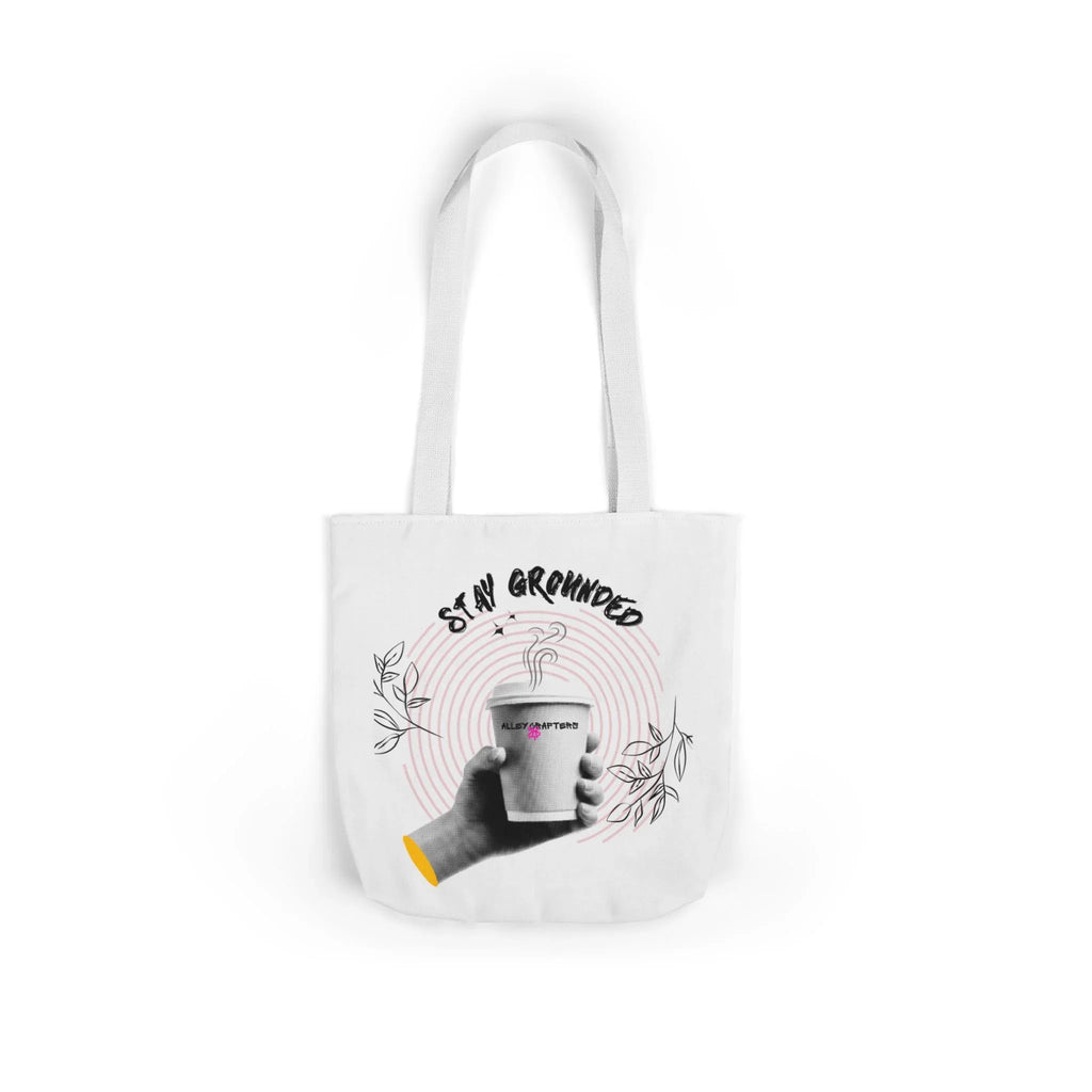 White coffee tote with white handles, “STAY GROUNDED” coffee mug graphic on front