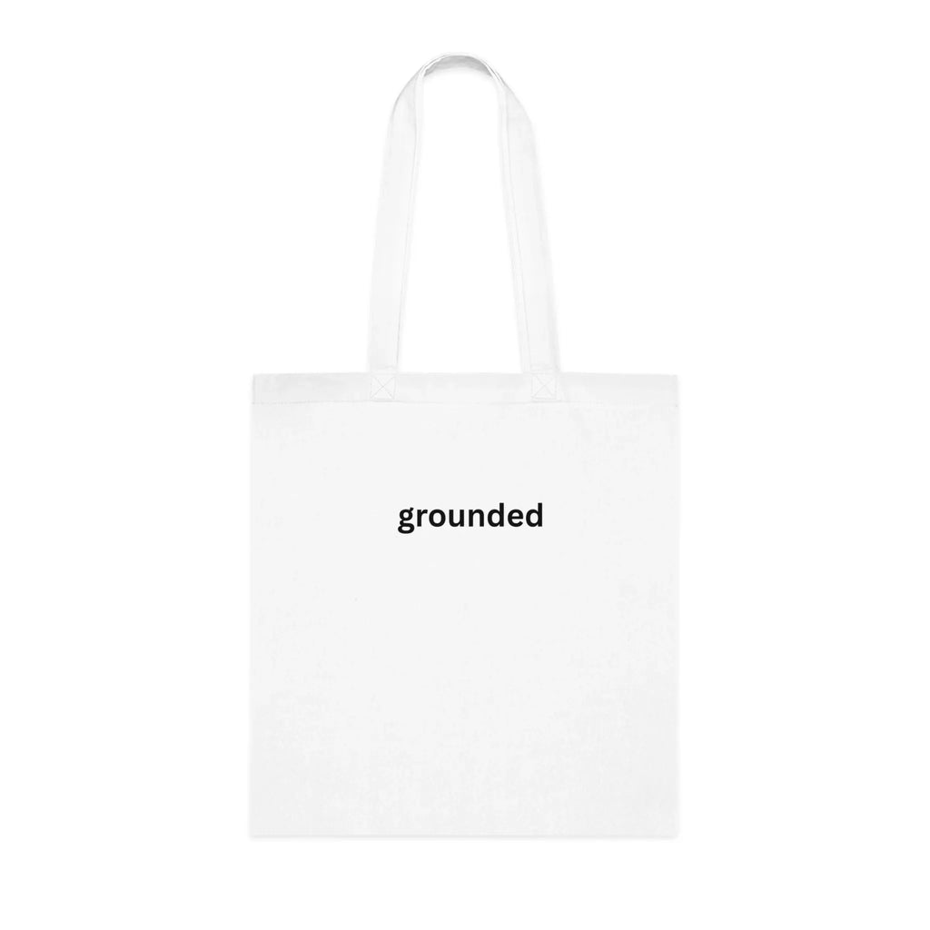 White cotton tote bag with two short handles, centered “grounded” print