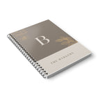 A5 notebook with taupe cover, gold monogram B, floral accents, and spiral binding.