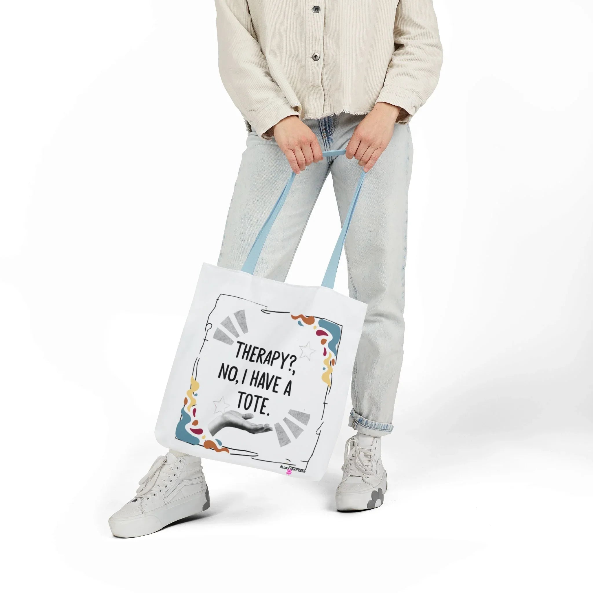 White canvas tote bag with printed quote and colorful doodles, hanging from hands.