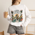 White unisex sweatshirt with “GOOD ENERGY” botanical bird graphic on front