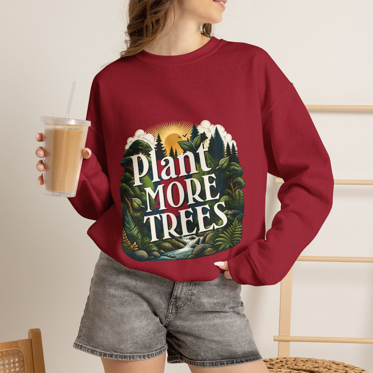 Unisex red sweatshirt worn with “Plant More Trees” nature graphic on front