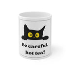 White ceramic mug with black cat and yellow eyes, 'Be careful, hot tea!' text