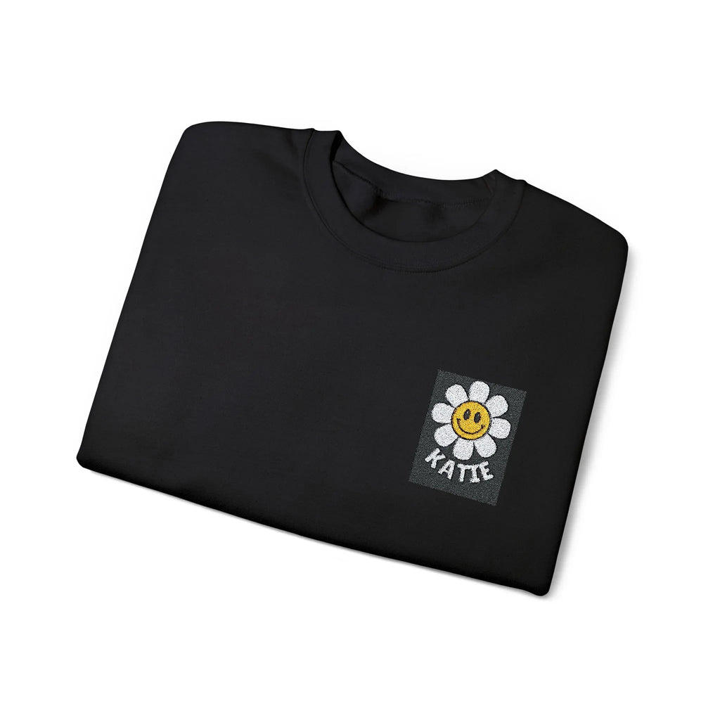 Black crewneck sweatshirt with flower smiley square patch at center chest.