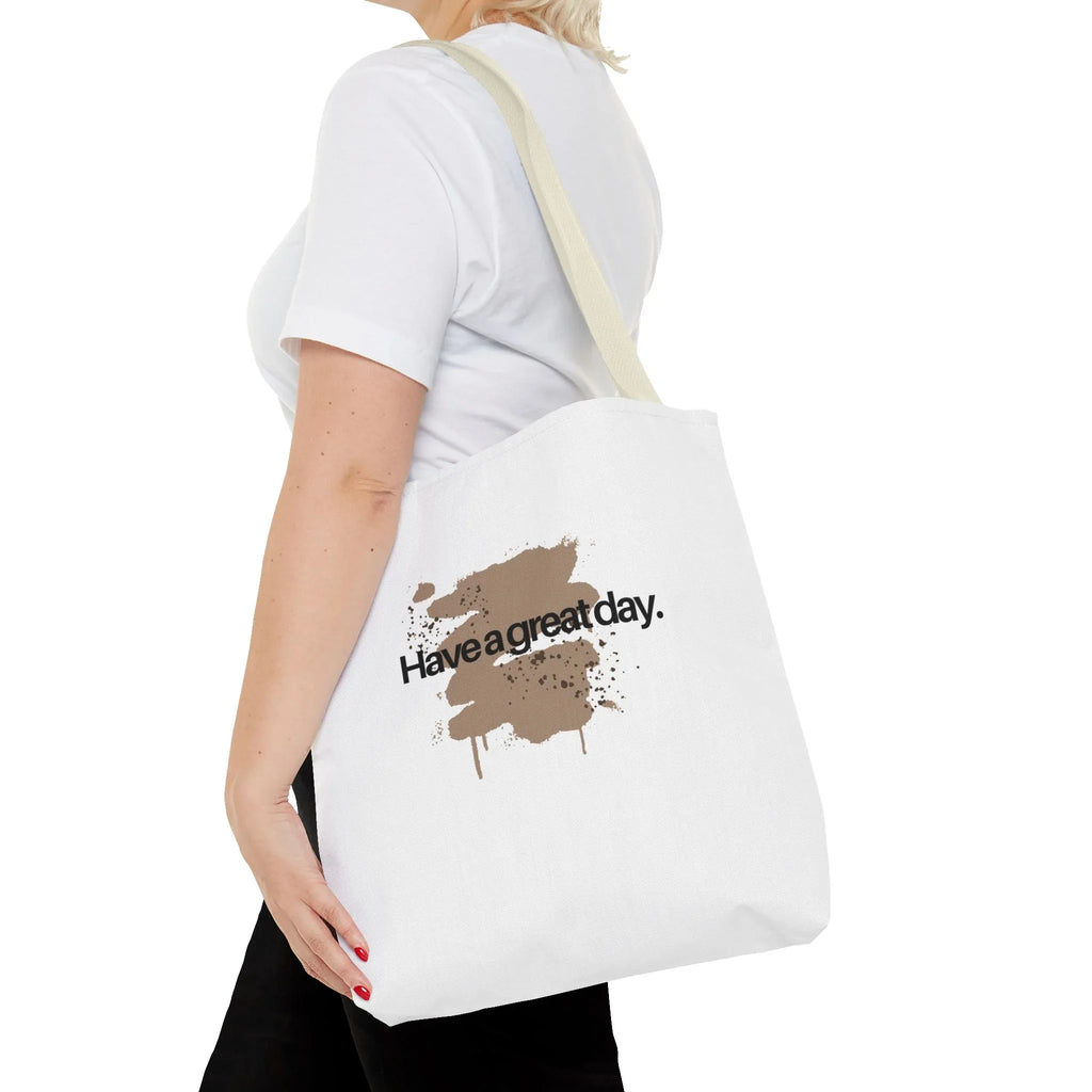 White canvas tote bag with light tan handles and brown splash “Haveagreatday.”