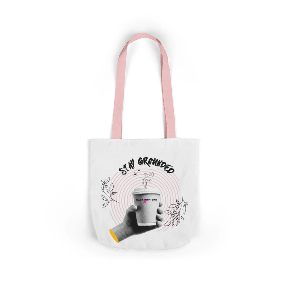 White coffee tote with pink handles, “STAY GROUNDED” coffee mug graphic on front