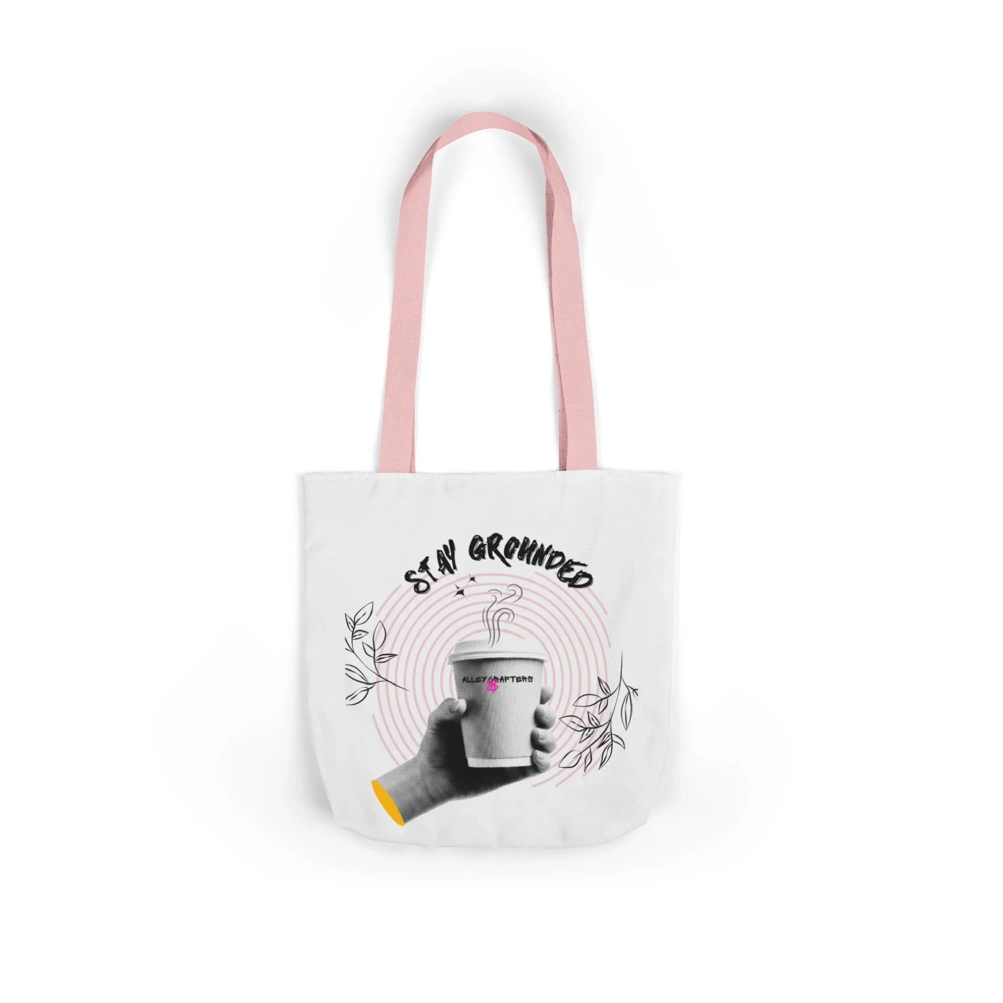 White coffee tote with pink handles, “STAY GROUNDED” coffee mug graphic on front