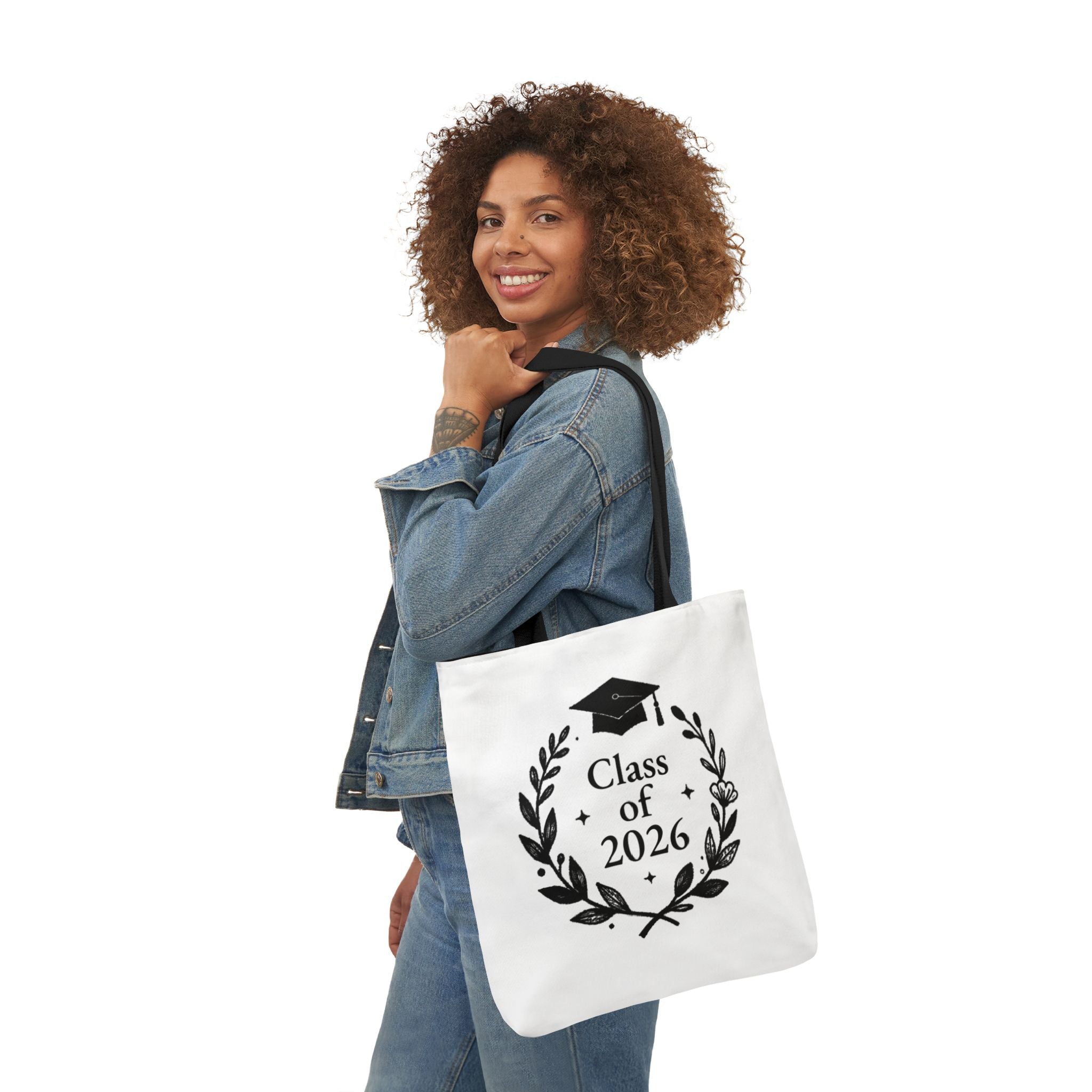 White tote bag with Class of 2026 wreath and graduation cap, carried by person