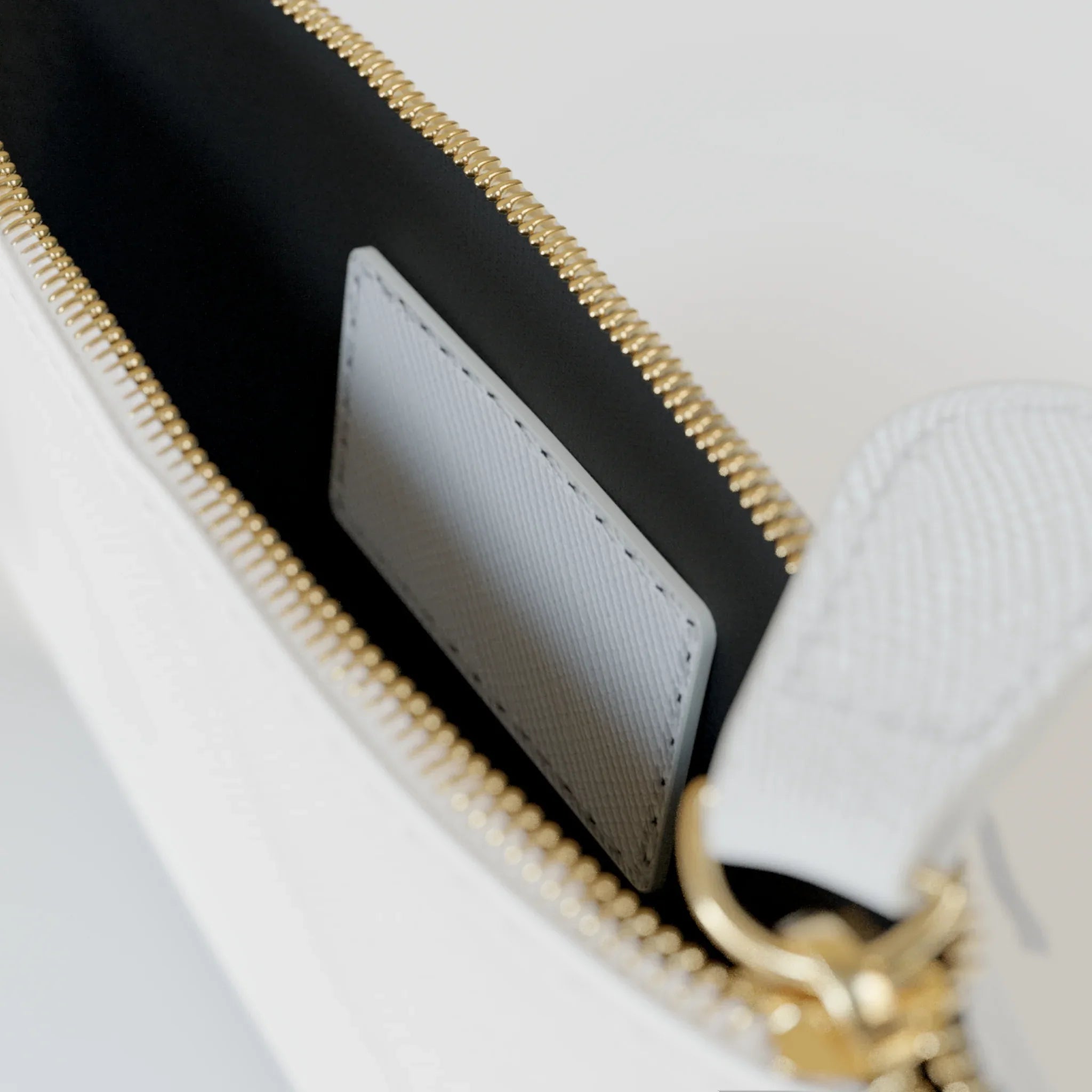 Mini clutch bag interior with dark lining, card slot, and gold zipper edge
