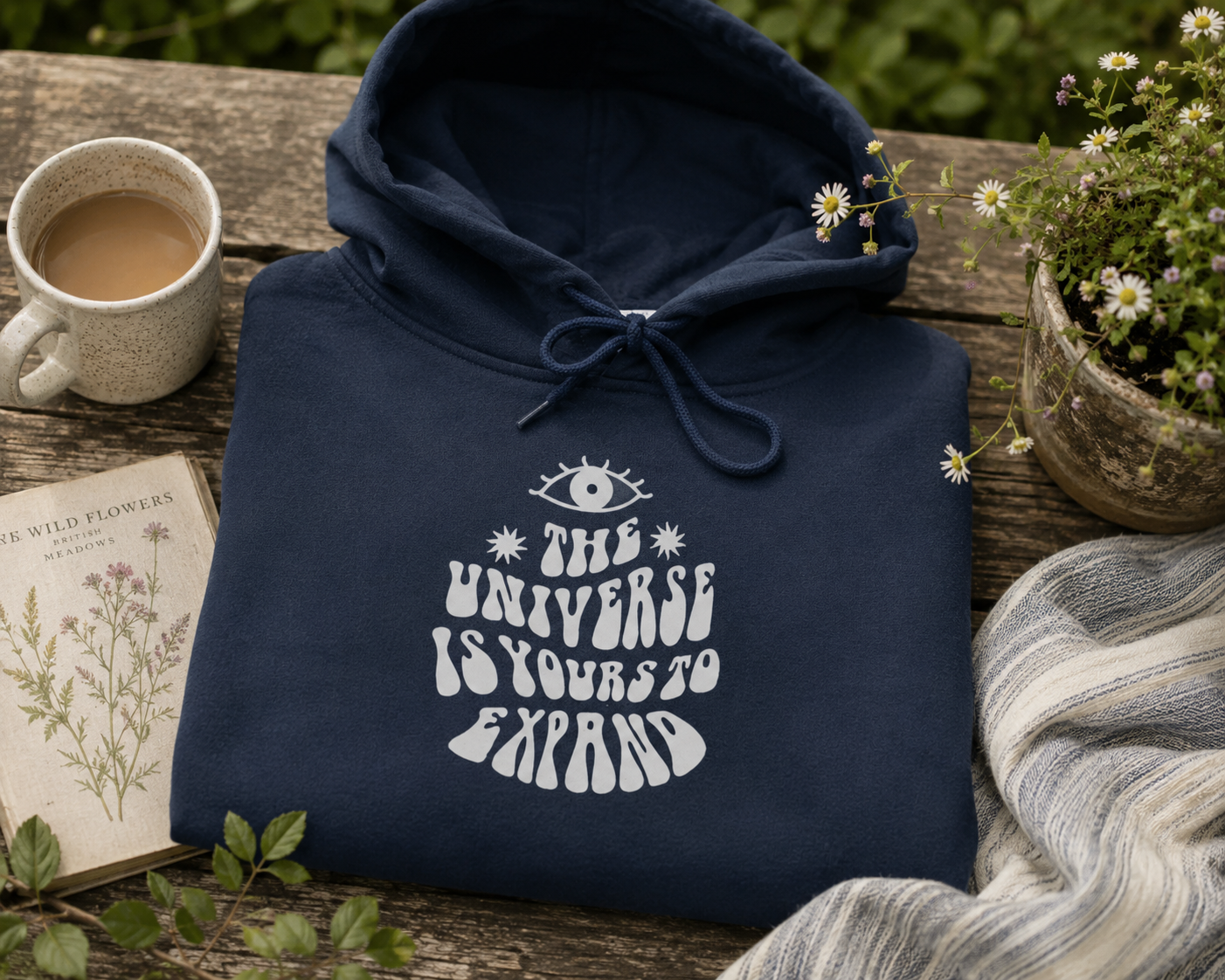Navy hoodie on a bench; hood with drawstrings and front graphic print