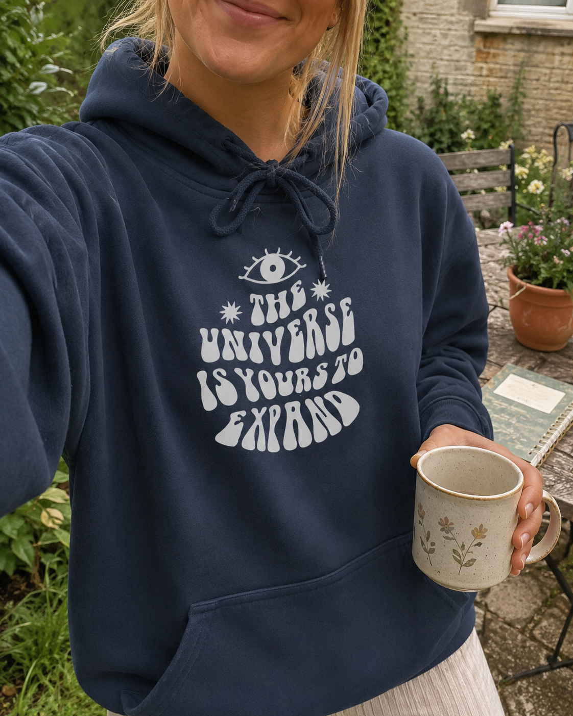 Navy hoodie with hood drawstrings and kangaroo pocket; white eye and text graphic