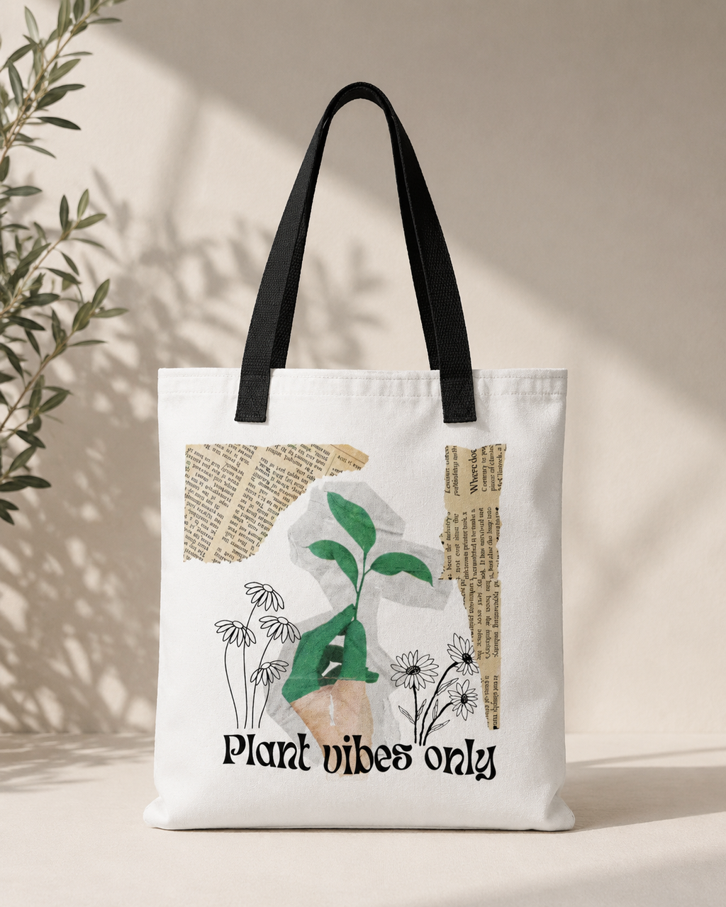 A white canvas tote bag with black shoulder straps, featuring a plant-themed graphic print with the text 'Plant vibes only' and a green sprout illustration, set against a warm beige background with soft leaf shadows.